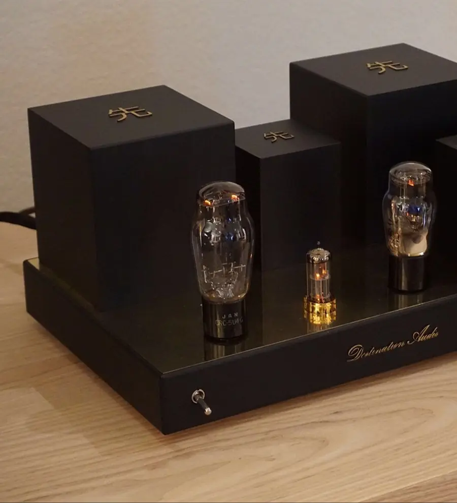A Destination Audio 45 tube mono amplifier with glowing tubes on a light wood table