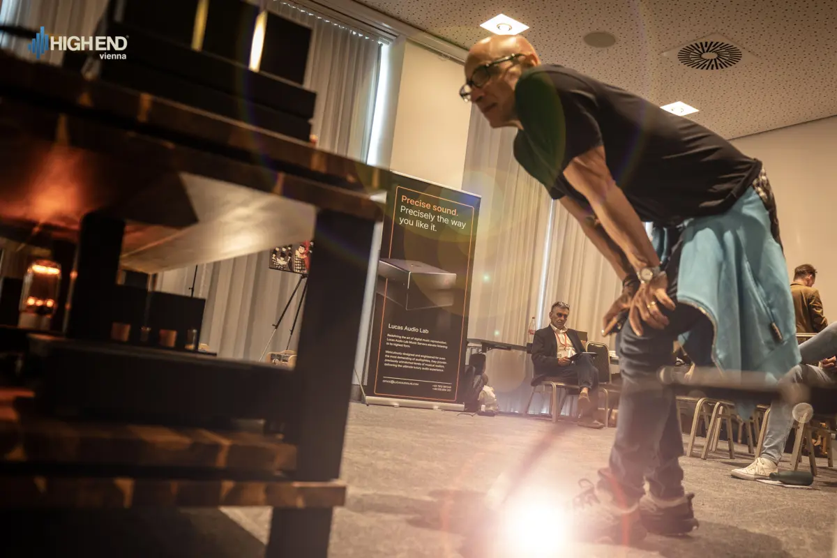 A visitor leaning forward beside the equipment rack in the Destination Audio room at High End Vienna