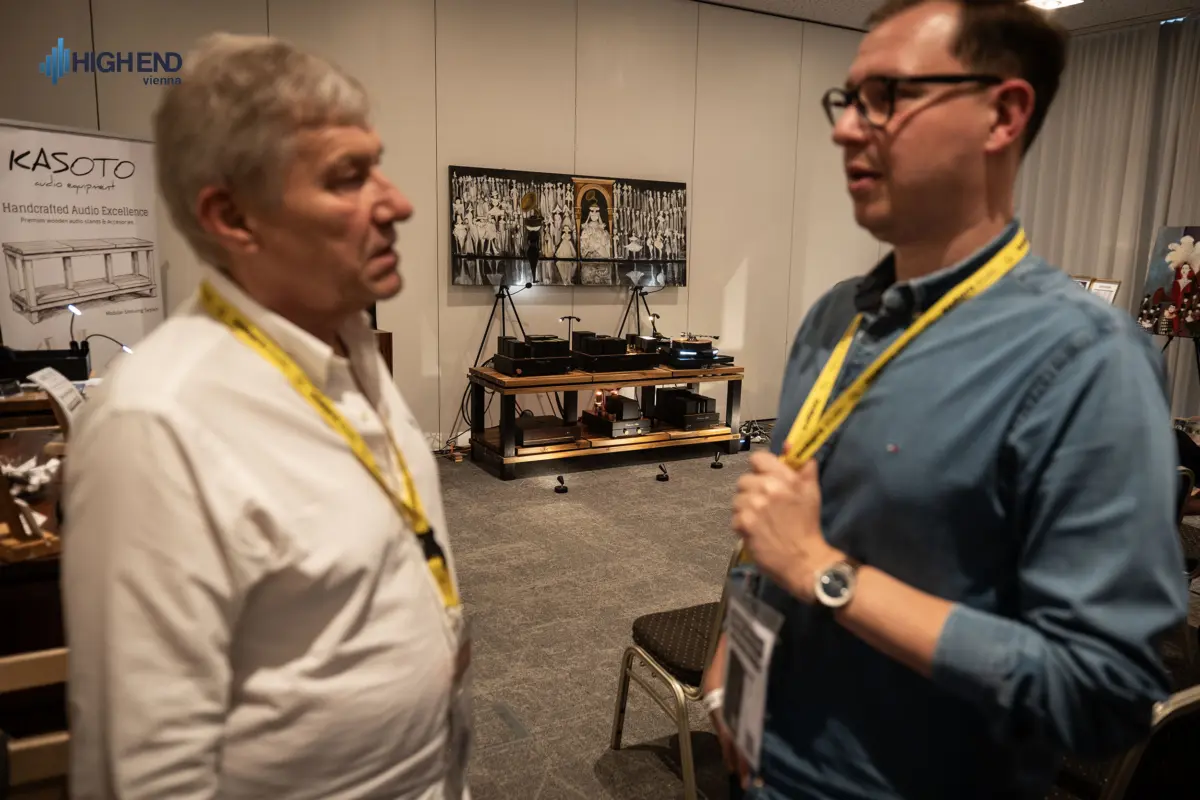 Two men talking in front of the Destination Audio room at High End Vienna, with the equipment rack in the background
