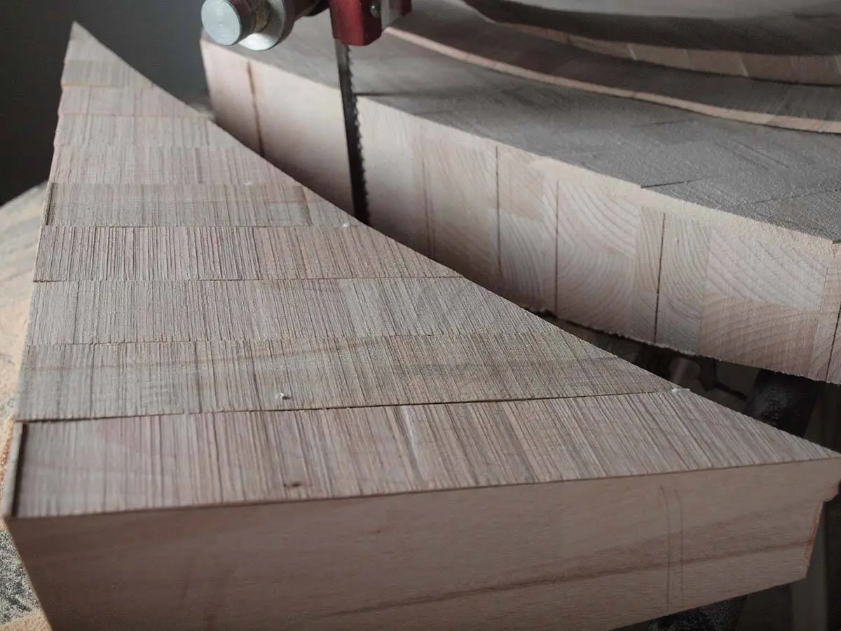A band saw cutting a stack of beech wood blocks glued together for a horn