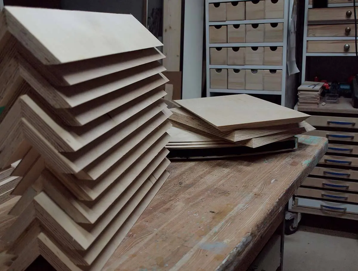 Stacks of cut plywood pieces on a workbench in the workshop