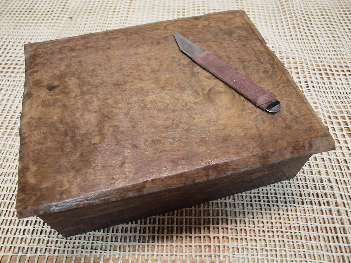 A small burl wood box with a marking knife lying on its lid